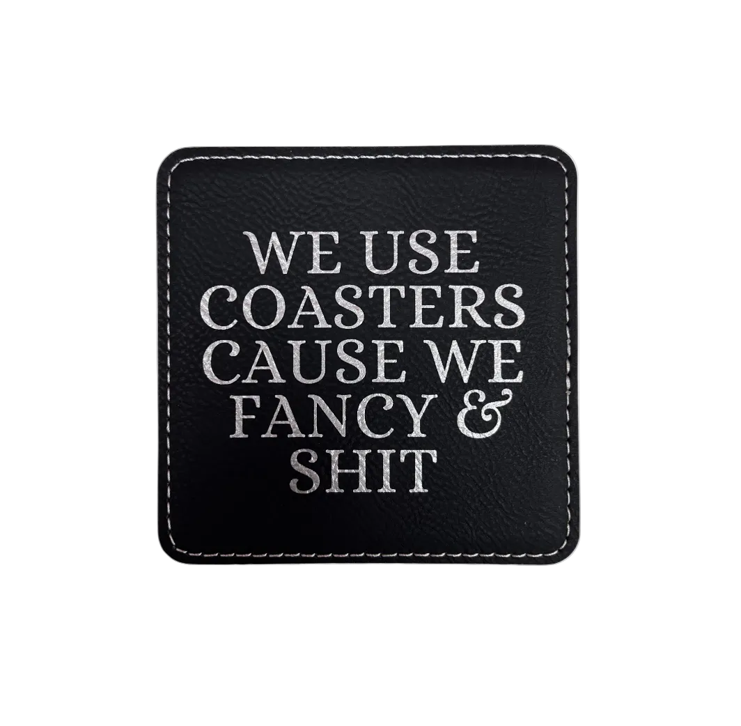 Black Leatherette coasters engraved with text 'We use coasters we fancy & shit"