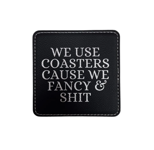 Black Leatherette coasters engraved  with text 'We use coasters we fancy & shit"